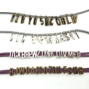 Detailed view of alloy capital letter pendants on suede cords for DIY jewelry making
