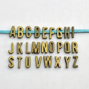 Detail view of 26 antique bronze letter beads arranged on string for DIY jewelry making