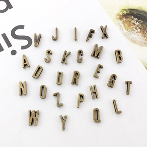 Macro shot of 26 antique bronze alloy alphabet charms from A to Z for DIY jewelry making