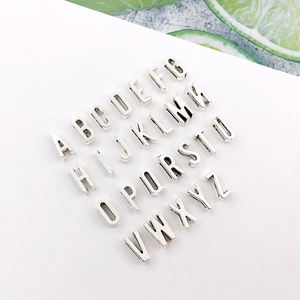 Macro detail of 26 antique silver alphabet metal charms for DIY jewelry making kits