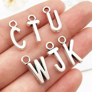 Close-up of small vintage silver alloy letter charms for DIY jewelry making