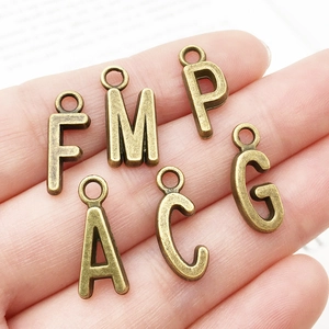 Close-up of vintage bronze alloy alphabet pendants for DIY jewelry making accessories