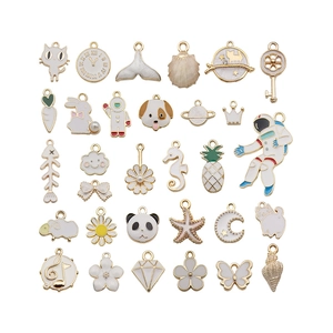 Assorted white enamel and gold alloy charms featuring astronaut, cat, and floral designs