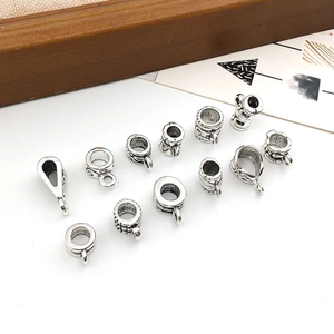 Variety of silver alloy spacer beads and bail charms for jewelry making on white background