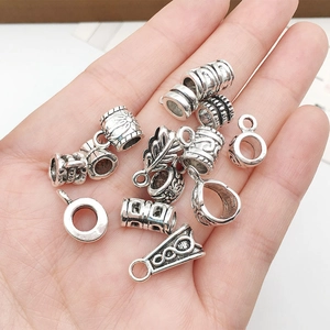 Macro view of vintage silver alloy spacer beads and leaf pendants held in hand