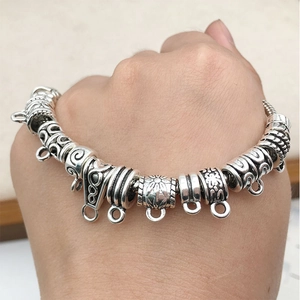 Macro view of retro silver beads with floral patterns and DIY charm dangles on bracelet