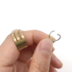 Detail of hollow gold multi-row open ring and silver ear cuff held on white background