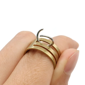 Detail of gold multi-layer brushed metal ring with contrasting silver hoop charm