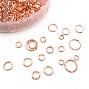 Macro shot of rose gold jump rings in various sizes with a transparent organizer box
