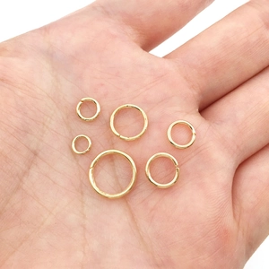 Detail showing various sizes of golden open jump rings for DIY jewelry on a hand