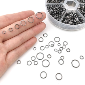 Close-up of assorted gunmetal jump rings in a 6-grid storage box for DIY jewelry