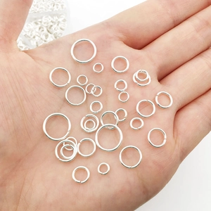 Close-up of mixed size silver open jump rings held in hand for jewelry making scale