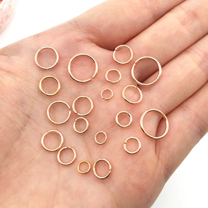Detail view of multi-size rose gold jump rings for jewelry making held in a palm