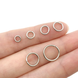 Size comparison of silver open jump rings in six sizes against a human finger