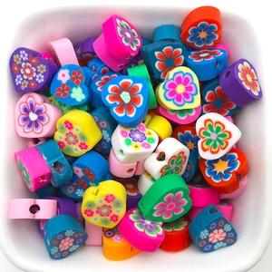 Perles en argile polymère colorées en forme de cœur avec motifs floraux dans un bol