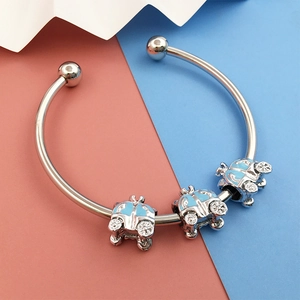 Detail of silver pumpkin carriage charms with blue enamel on a stylish open bangle