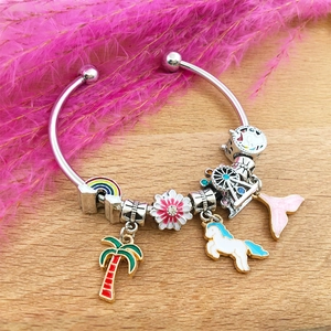 Detailed view of enamel charms with rainbow and unicorn on a silver metal bracelet