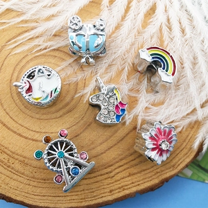 Detailed view of colorful enamel unicorn, rainbow, and star beads on a rustic wooden tray