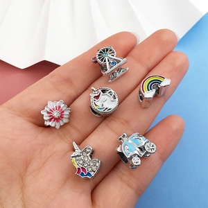 Macro detail of rainbow unicorn and Ferris wheel charms for DIY bead bracelets