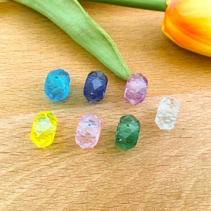 Vista plana de cuentas acrílicas facetadas de colores sobre madera para hacer joyas DIY