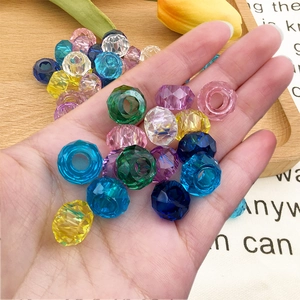 Vista macro de cuentas de acrílico facetadas de colores para joyas en la mano