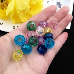 Primer plano de cuentas acrílicas facetadas de colores para joyas DIY en una mano
