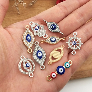 Detailansicht von Evil Eye und Hamsa Anhängern aus Legierung für DIY-Schmuck in der Hand