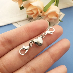 Handheld view of a silver heart-shaped magnetic clasp connector with dual lobster claws