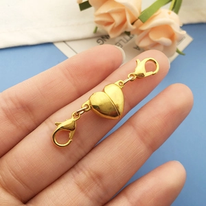 Close-up of golden heart-shaped magnetic clasp with lobster claws for jewelry DIY