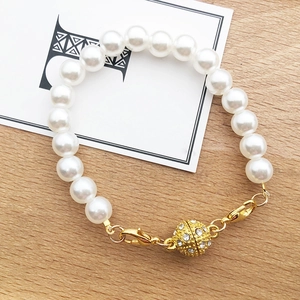 Detail of pearl bracelet featuring a gold magnetic clasp with sparkling rhinestones