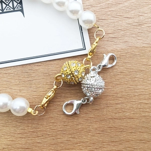 Macro detail of rhinestone magnetic clasps in gold and silver on a pearl necklace