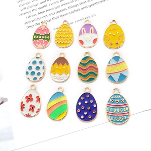Flat lay of 12 colorful Easter egg charms with enamel bunny and chick patterns on white background