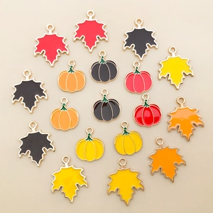 Detail of colorful enamel maple leaf and pumpkin pendants with gold metal frames for DIY crafts