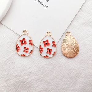 Easter egg jewelry pendant with white enamel red floral pattern and gold metal base