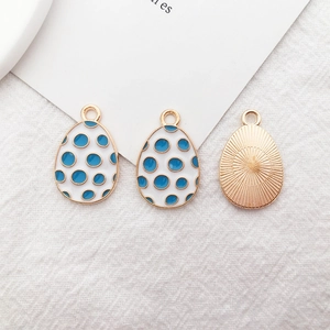 Detail of Easter egg alloy pendant with white blue dots and gold sunburst texture