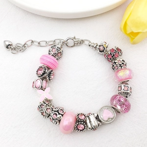Detail of pink charm bracelet with glass beads, enamel hearts and floral metal spacers