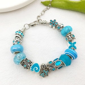 Detailed view of blue murano glass beads and floral silver charms on a DIY bracelet