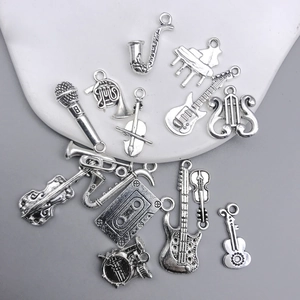 Detailed close-up of antique silver music charms including guitar and violin for jewelry