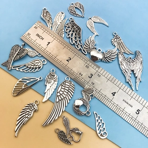 Antique silver wing charms and heart pendants for DIY jewelry making on blue background
