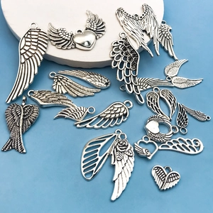 Detailed macro view of vintage silver alloy dragonfly and feather charms for DIY jewelry