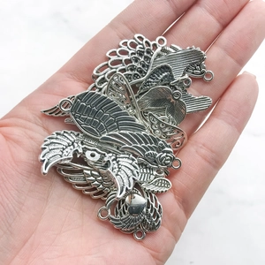 Macro detail of vintage silver alloy wing charms with intricate feather textures for DIY jewelry