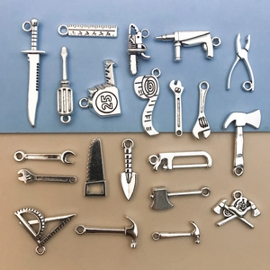 Detailed close-up of antique silver alloy tool pendants including wrench and hammer shapes