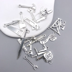Macro shot of silver alloy mini tool charms including hammer, wrench and ruler details