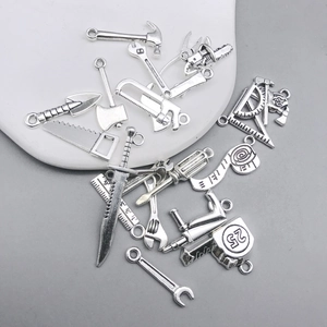 Macro detail of various antique silver mini tool pendants including hammer and saw