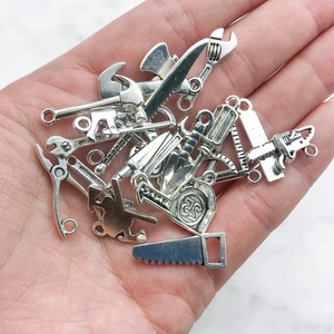 Macro view of vintage silver alloy tool charms including saws and hammers for DIY crafts
