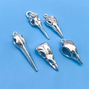Detailed view of five gothic silver bird skull charms for DIY jewelry making