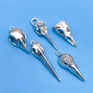 Macro view of five distinct silver Gothic bird skull pendants with ornate engravings