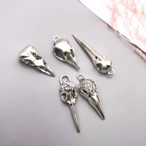 Set of five gothic crow skull pendants in vintage silver finish on a smooth surface