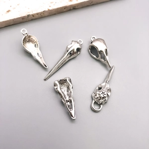 Detailed macro view of five vintage silver gothic bird skull charms for DIY jewelry making