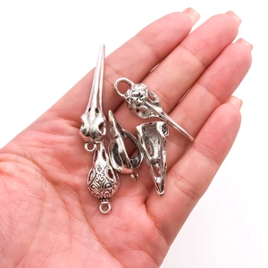 Set of four gothic vintage silver bird skull pendants for men shown in hand for scale